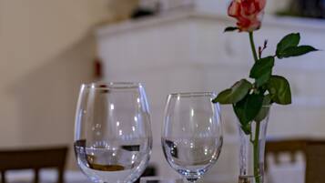 A dining table with two wine glasses and a vase with a rose.