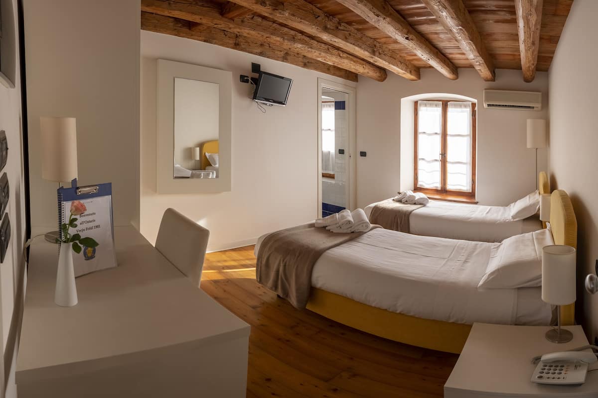 Een hotelkamer met twee bedden, een bureau, een stoel, een spiegel, een televisie en een telefoon.