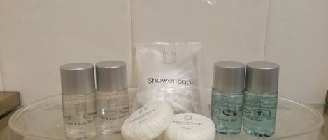 Une étagère de salle de bain contenant divers produits de toilette, notamment du shampoing et du gel douche, ainsi qu’un bonnet de douche.
