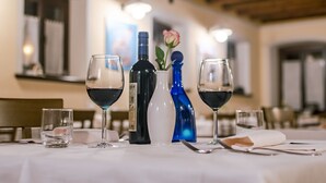 Een eettafel gedekt met wijnglazen, een fles en een vaas met een roos.