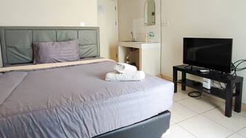 Une chambre d’hôtel avec un lit, un téléviseur posé sur un meuble, un lavabo et un miroir.
