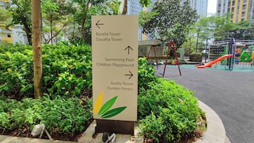 Un letrero direccional con flechas que indican varios servicios, como piscina, parque infantil y zona de fitness al aire libre.