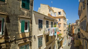 A narrow street with buildings featuring balconies and shutters.