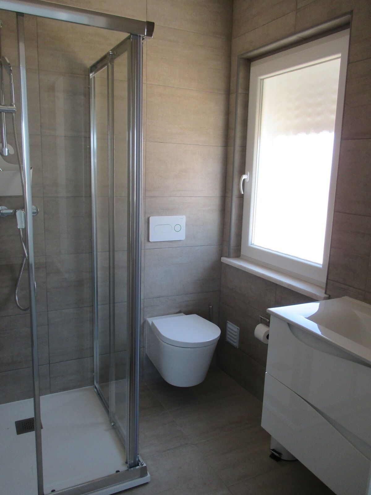 Un bagno moderno con cabina doccia in vetro, un water e un lavandino.