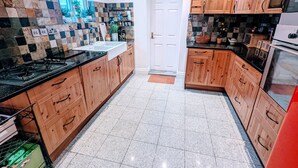 Een keuken met houten kastjes, een zwart aanrecht, een betegelde spatwand en een roestvrijstalen fornuis.