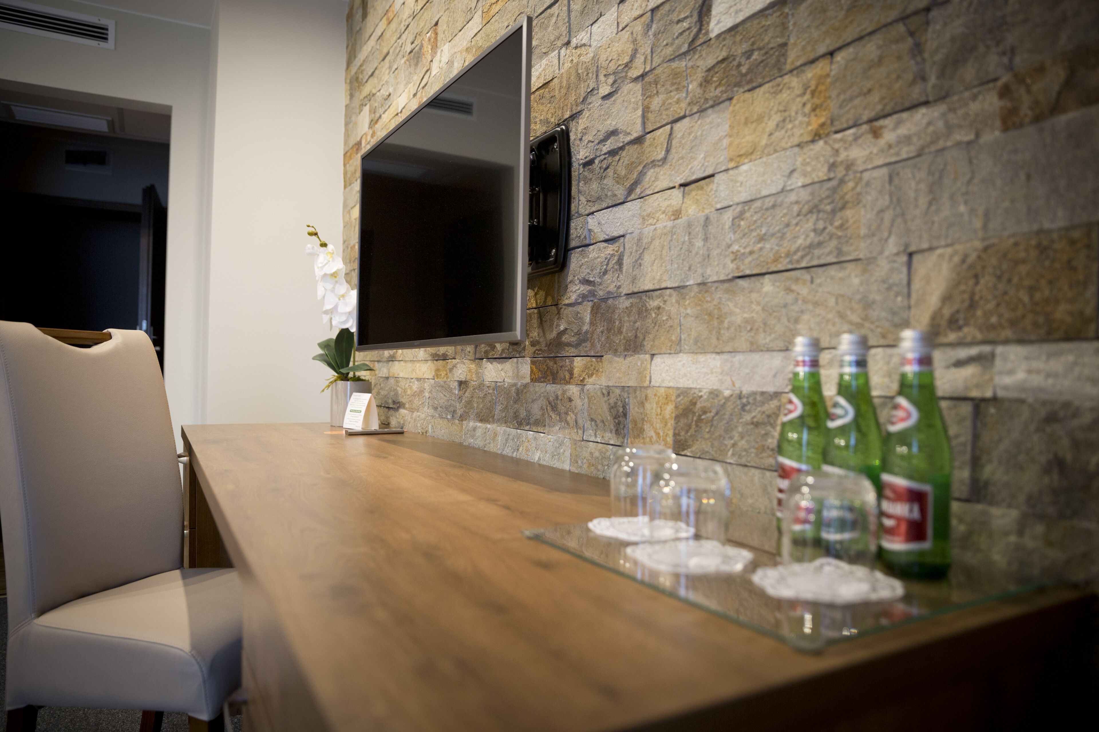 Una cocina moderna con salpicadero de piedra, un televisor de pantalla plana sobre la encimera y una zona de bar con vasos y botellas.