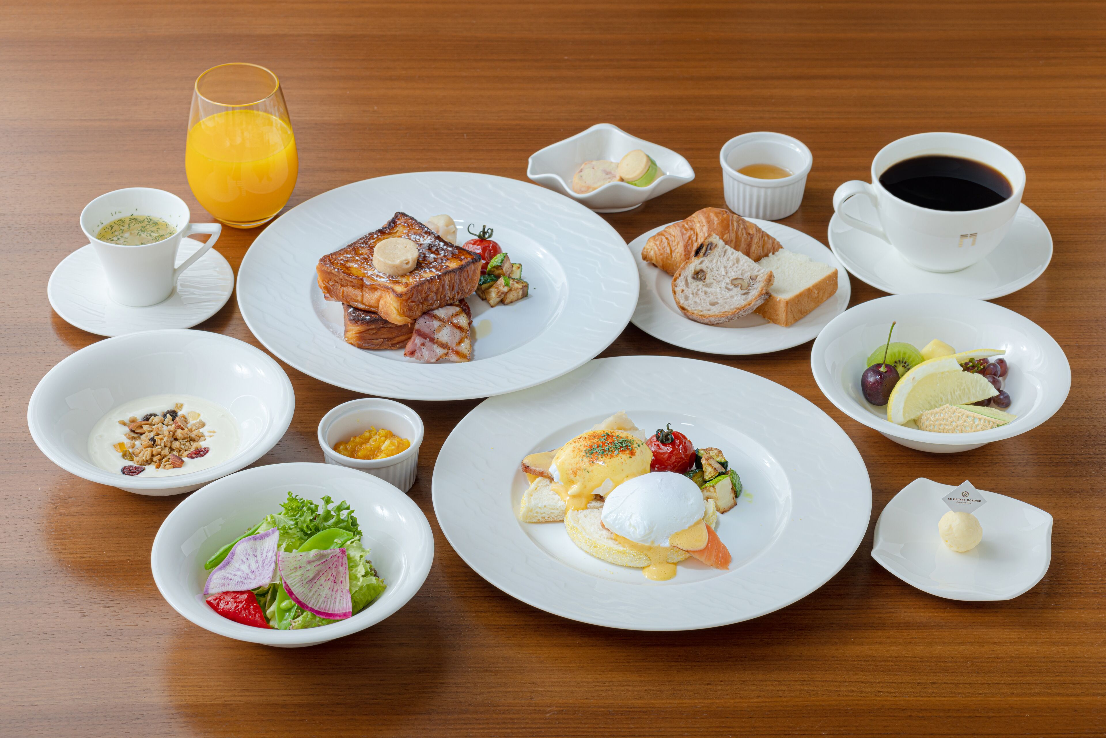 Un desayuno con diversos platos y bebidas sobre una mesa de madera.