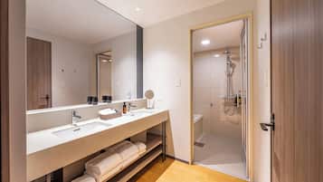 Un baño moderno con un espejo grande, dos lavamanos, una ducha y piso de madera.
