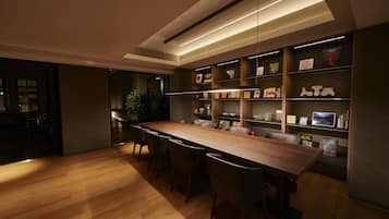 A modern dining area with a long wooden table, several chairs, and built-in bookshelves with various items.