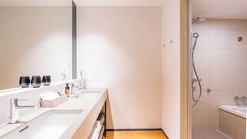 A modern bathroom with two sinks, a shower, and a large mirror.