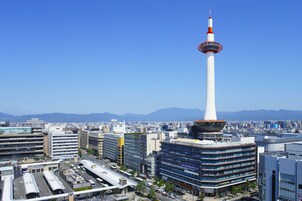 A modern building with a prominent tower, multiple floors, and a parking area.