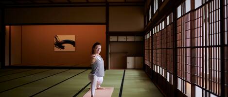 A person practicing yoga on a tatami mat in a room with traditional Japanese sliding doors and a wooden ceiling.