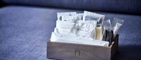 Una caja de madera con artículos de cortesía del hotel, como juegos de algodón, turbante para el cabello, gorro de ducha y productos de aseo.