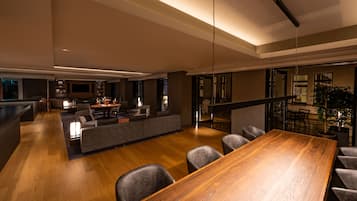 Una sala de estar moderna con una mesa de comedor de madera, sofás grises y un televisor montado en la pared.