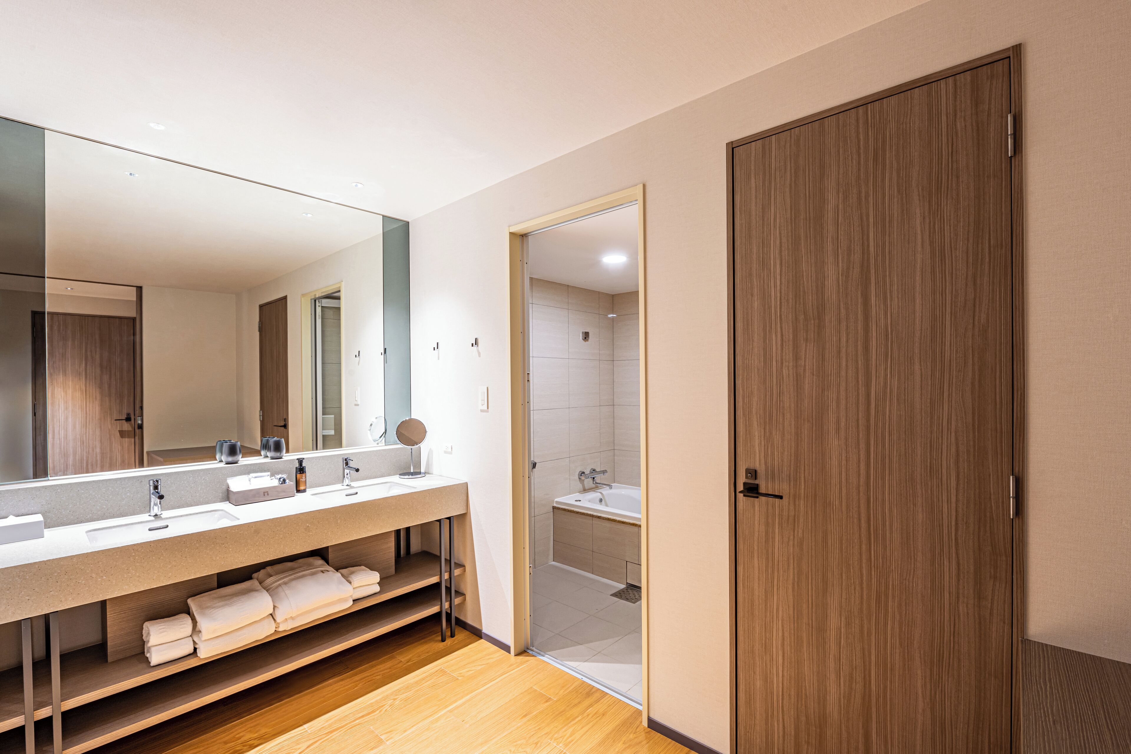 Un bagno moderno con un ampio specchio, due lavandini e una zona doccia.