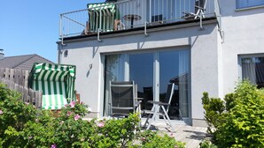 Uma casa de dois andares com varanda, porta de correr e cerca de madeira.