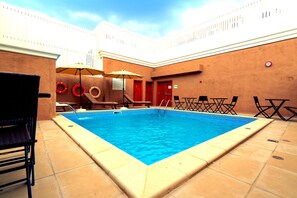 Une piscine avec des chaises longues et un parasol.