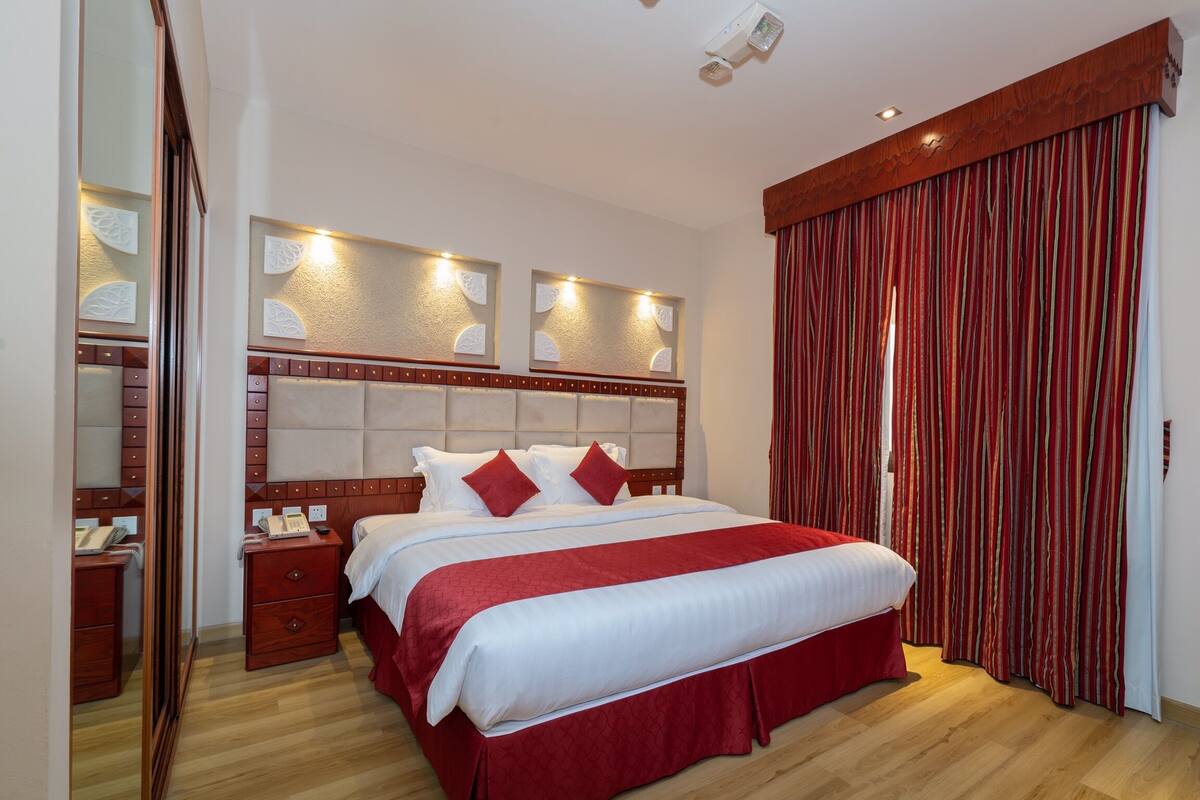 A bedroom with a large bed, wooden headboard, bedside tables, and a mirror.