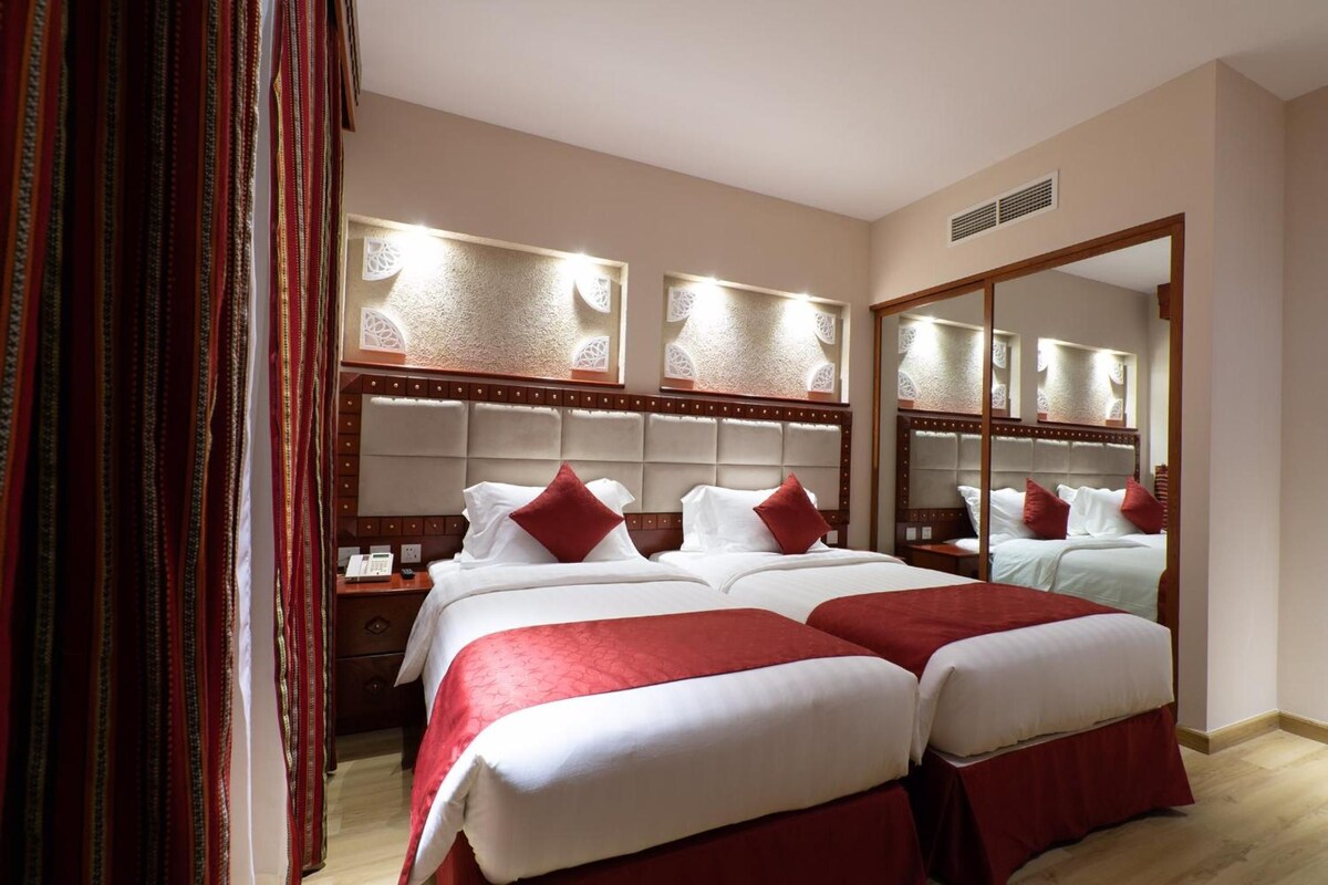 Quarto de hotel com duas camas, um espelho grande e um telefone na mesa de cabeceira.