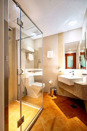 Une salle de bain moderne avec une douche à parois de verre, un lavabo doté d’un plan de travail en granit et un miroir au-dessus du lavabo.