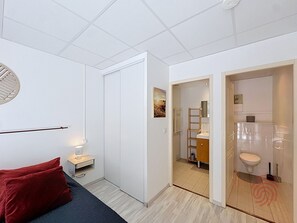 A modern bedroom with a bed, bedside table, and a red pillow.