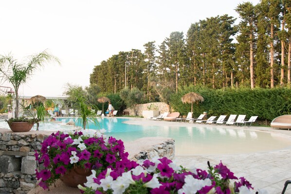 A swimming pool with lounge chairs, surrounded by greenery and trees. - Bellaria Residence (Giurdignano)