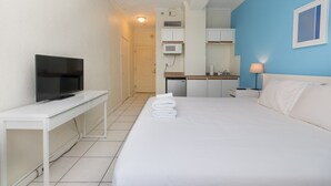 Une chambre d’hôtel équipée d’un lit, d’une télévision, d’un bureau, d’un four à micro-ondes et d’une kitchenette.