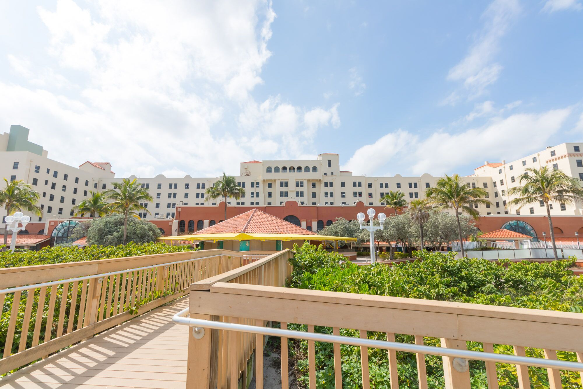 A hotel with multiple buildings, a wooden deck, and palm trees.