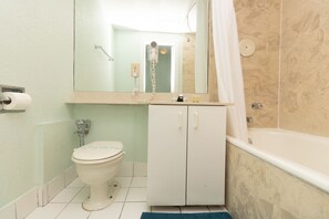 A bathroom with a toilet, a sink with a mirror, and a bathtub. - 626 Ocean View Hollywood Studio (Hollywood)