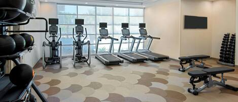 Ein Fitnessstudio mit Laufbändern, Crosstrainern und Gewichten.