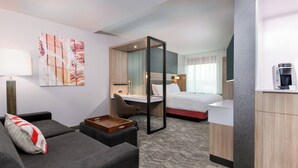 Ein Hotelzimmer mit Sofa, Schreibtisch, Bett und einer Kaffeemaschine.
