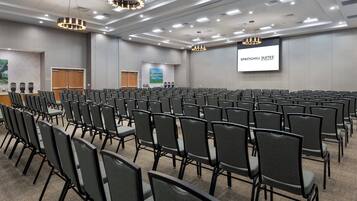 A conference room with rows of chairs, a projector screen displaying 'SPRINGHILL SUITES BY MARRIOTT', and a large screen with a landscape image.