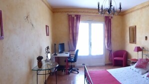 A bedroom with a bed, a desk, a chair, and a window with curtains. - Bed and Breakfast in a 19th century Bastide in a large park with swimming pool (Roquevaire)