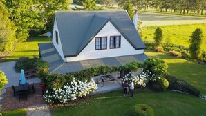 Une maison avec un toit en pente, entourée d’une pelouse bien entretenue et d’arbustes en fleurs.