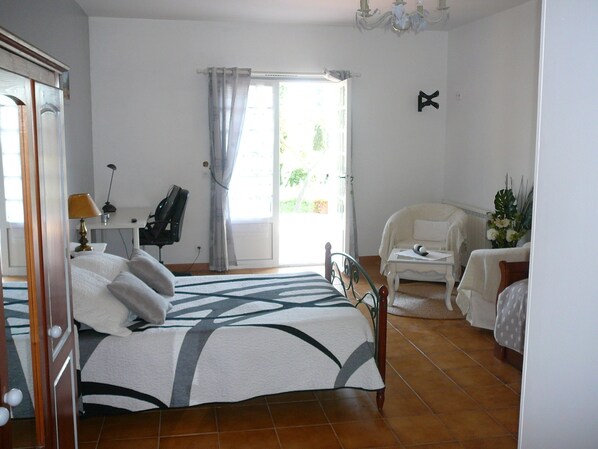 Un dormitorio con cama, escritorio, silla, sofá y ventana con cortinas.