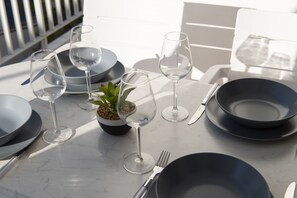 A table set with wine glasses, plates, and cutlery, with a small potted plant in the center. - Downtown Apartment Paroikia (Paroikia Paros)