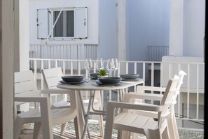 Une table ronde entourée de chaises blanches, sur laquelle sont disposés des bols, des verres et une petite plante.