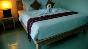 A neatly made bed with a decorative swan and rose, a wooden headboard, and a bedside lamp. - Agatha Canggu (Canggu)