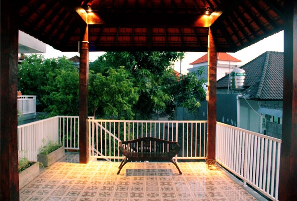 A covered outdoor area with a bench, tiled flooring, and a railing. - Agatha Canggu (Canggu)