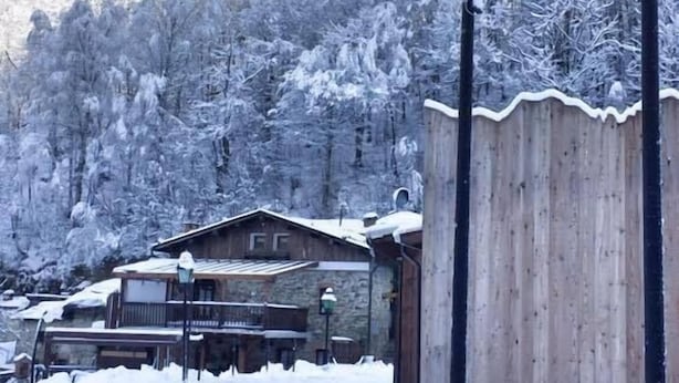 Una montaña nevada con un edificio de madera y un letrero de B&B Barcollo.