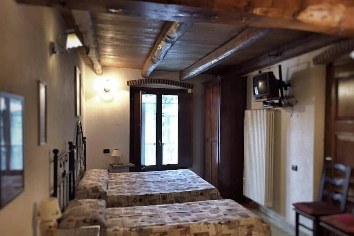 A narrow hallway with a bed at the end, a radiator, and a television on the wall.