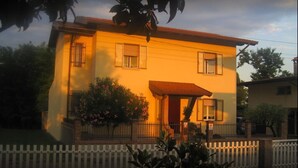 A two-story house with a red-tiled roof, a small porch, and a white picket fence. - B&B Ca Di Me (Premariacco)