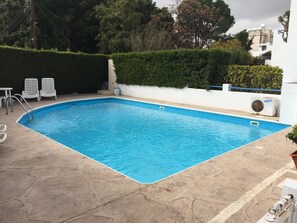 A rectangular swimming pool with a clear blue water surface, surrounded by a stone deck.