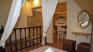 A bedroom with a bed, a chair, a mirror, and a small table. - Yro Studios (Chania)