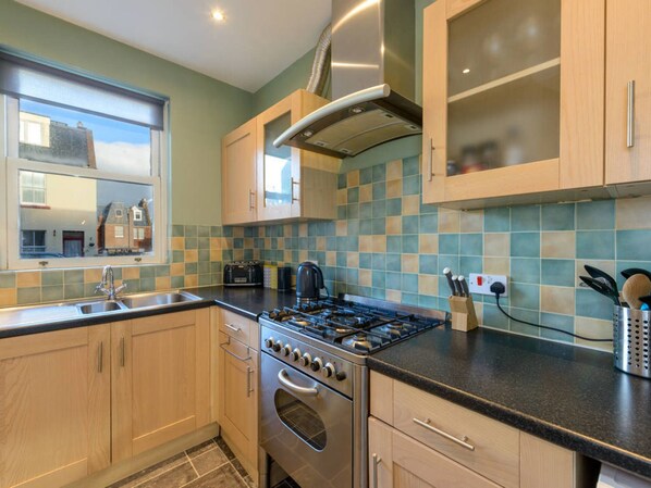 A modern kitchen with wooden cabinets, a gas stove, and a large window. - Craigleith Lodge (North Berwick)