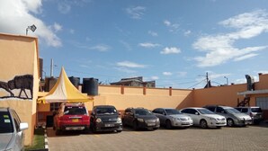 A parking lot with several cars parked in front of a building with a yellow tent and a mural of a bull. - Mayors Resort Centre (Nairobi)