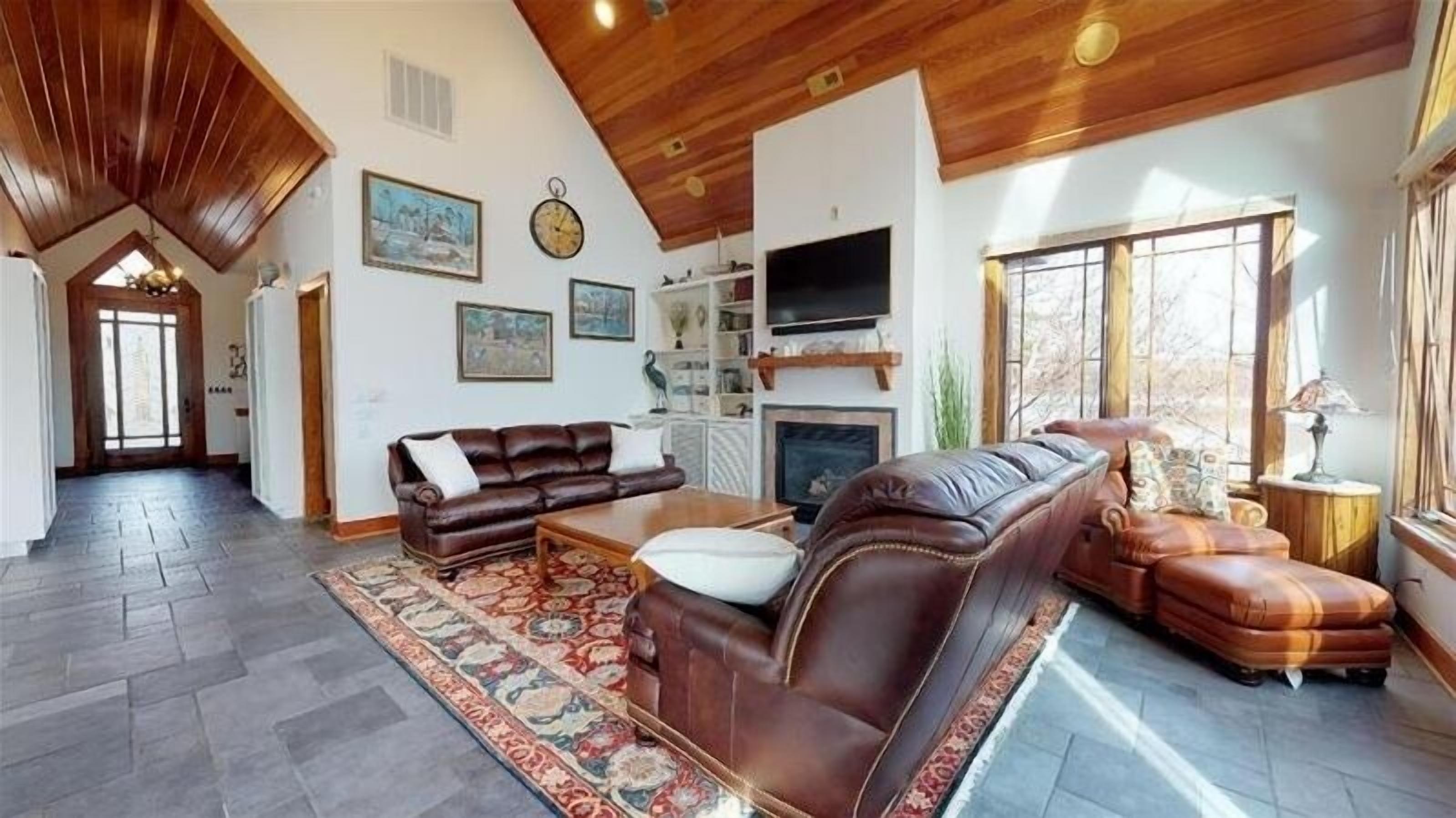 Ein geräumiges Wohnzimmer mit hoher Decke, Kamin und großem Fenster.
