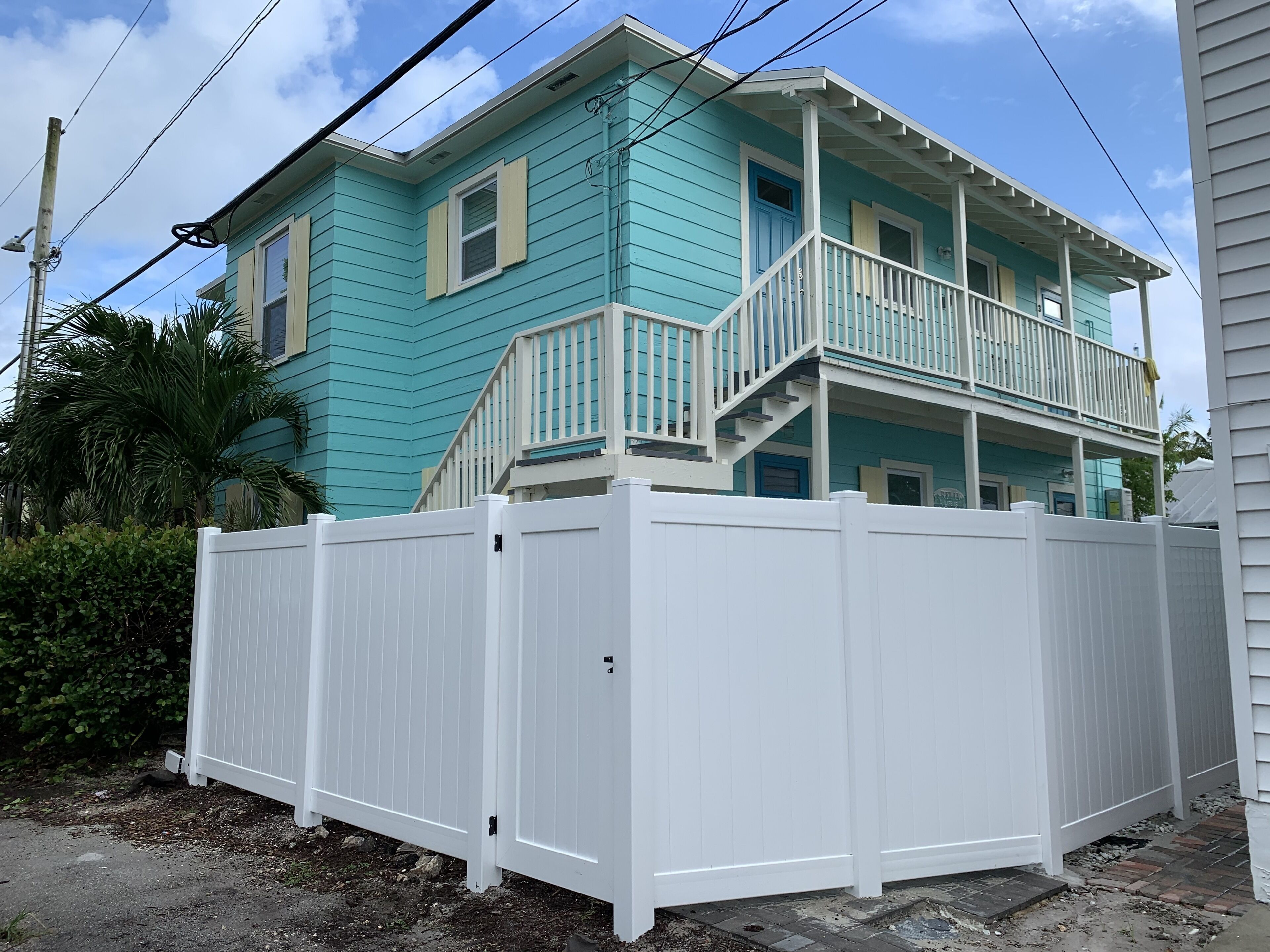 A two-story house with a balcony and a white fence.
