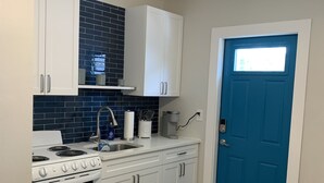 A kitchen with white cabinets, a stove, and a blue door.