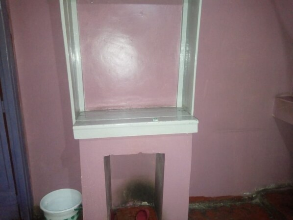 A room with a pink wall, a white-framed window, and a small white bucket.